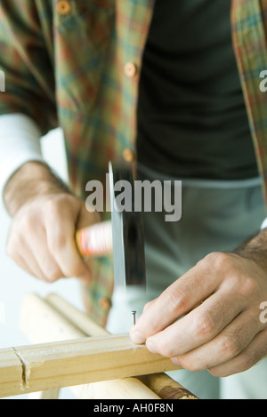 Mann Hämmern Nagel ins Holz, verkürzte Ansicht Stockfoto