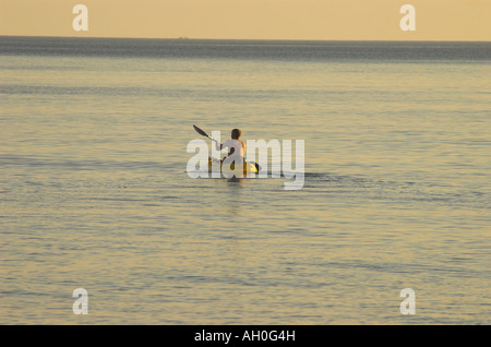 einsamer single Canooist im Kajak Paddel heraus zum Meer in der untergehenden Sonne Stockfoto