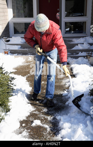 Mann leicht gebeugt mit Kopf nach unten gebogenen behandelt Schneeschaufel, um einem Schneehaufen auf Anhieb den geräumten Weg zu platzieren. Stockfoto