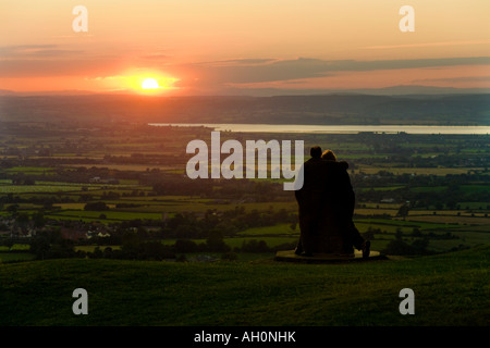 Ein paar den Sonnenuntergang von der Cotswold Böschung Sicht Frocester Hill angrenzenden Coaley Peak Picknickplatz, Gloucestershire Stockfoto