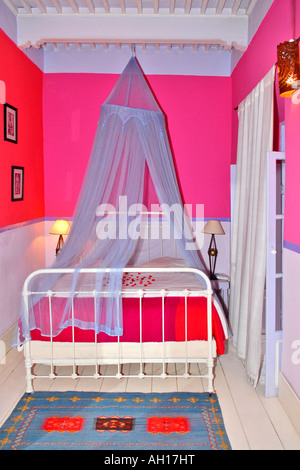 Marokko Essaouira, Riad El Madina Hippie Hotel, typisch afrikanischen Hotelszene der modernen rosa oder kirschrot Schlafzimmer mit Moskitonetzen Stockfoto