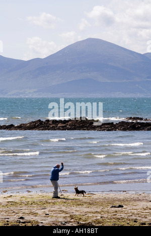 UK County Down Rossglass Mann zu Fuß Hund am Strand in Dundrum Bay in der Nähe von Mountains of Mourne Stockfoto