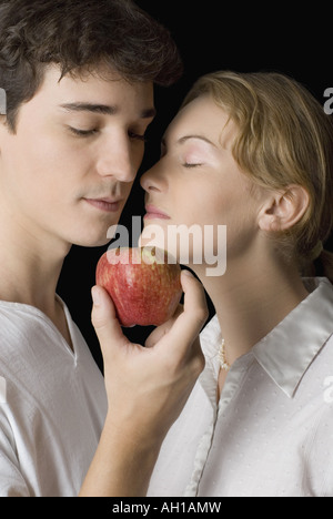 Nahaufnahme eines jungen Mannes, der einen Apfel, eine junge Frau den Mund geschlossen halten Stockfoto
