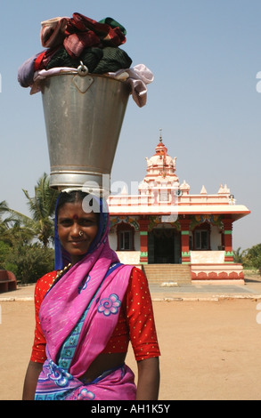 Inderin mit Eimer und Kleidung auf dem Kopf vor einen Hindu-Tempel, Karnataka, Indien Stockfoto