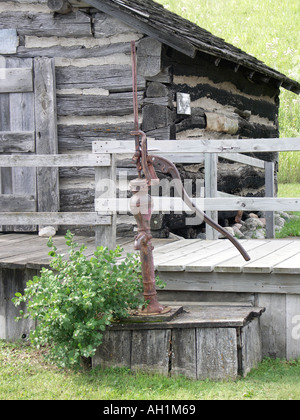 Hand-Wasserpumpe in Front des alten Blockhütte Stockfoto