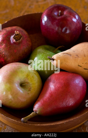 Ein hölzernes Schüsselchen gefüllt mit reifer Frucht, die Äpfel, Birnen und einen Granatapfel enthält. Dieses Foto sieht aus wie eine gemalte Stillleben. Stockfoto