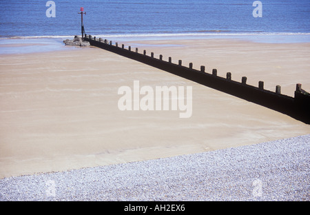 Blick auf weiten leeren Sandstrand mit grauen Kieselsteinen beschränkt auf oberen Strand und Buhne diagonal auf ruhiger See zugehen Stockfoto