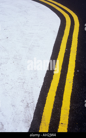 Detail der frisch gestrichenen gelbe Doppellinien geschwungene um eine weiße malte keine Access-Bereich auf neue Asphalt Stockfoto