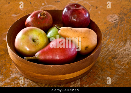 Ein hölzernes Schüsselchen gefüllt mit reifer Frucht, die Äpfel, Birnen und einen Granatapfel enthält. Dieses Foto sieht aus wie eine gemalte Stillleben. Stockfoto