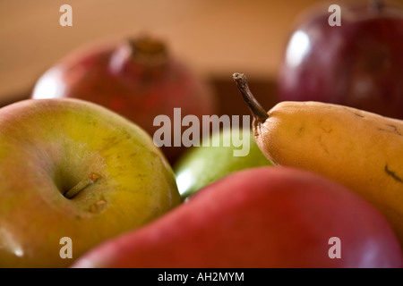 Eine Schüssel mit leckeren, reifen Früchten, die Äpfel, Birnen und einen Granatapfel enthält. Dieses Foto sieht aus wie eine gemalte Stillleben. Stockfoto