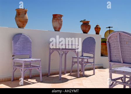 Essaouira, Marokko Riad El Madina, typisch afrikanischen Hippie Hotelszene Dachterrasse mit lila Wicker Tabelle & Stühle & Töpfe Stockfoto