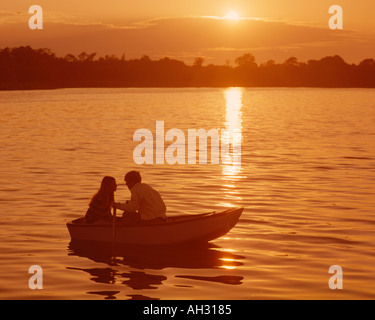 junges Paar im Ruderboot bei Sonnenuntergang Stockfoto