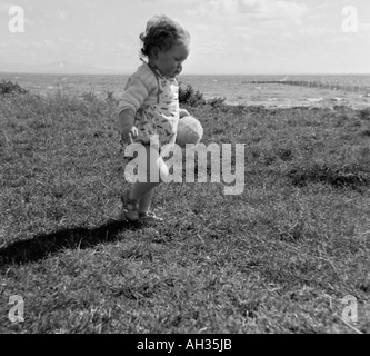 ALTE VINTAGE FAMILIENFOTOS SNAP SHOT VON KLEINEN MÄDCHEN LAUFEN IN GRASS FIELD UM 1950 Stockfoto