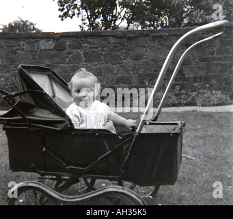 ALTE VINTAGE FAMILIE SNAPSHOT-FOTO VON BABY SITTING UND LÄCHELND IN ALTEN ALTMODISCHEN KINDERWAGEN Stockfoto