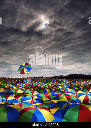 weiten Meer der farbigen farbigen Sonnenschirmen mit einem fliegenden entfernt in einem dunklen Himmel Regen Stockfoto