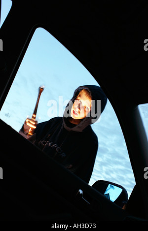 Auto Dieb junger Mann, Jugend mit Kapuze brechen ein Auto Stockfoto