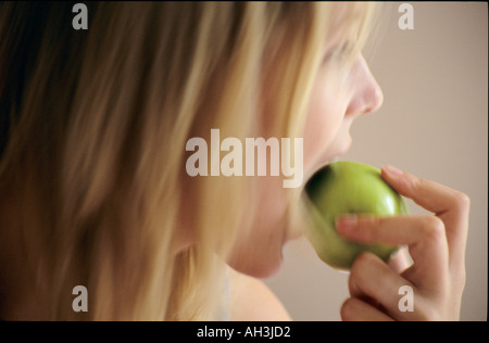 Junge Frau, die einen Apfel beißen Stockfoto