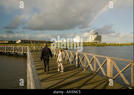 Mann und Kind auf Promenade mit Regenbogen über St David s Hotel und norwegische Kirche Cardiff Bay Wales UK Stockfoto