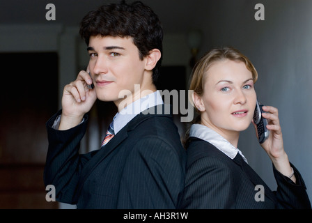 Porträt eines Geschäftsmannes und einer Geschäftsfrau stehen Rücken an Rücken und reden auf dem Handy Stockfoto