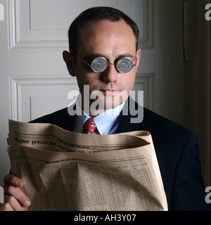 PORTRÄT EINES MANNES MIT US-DOLLAR-MÜNZE-BRILLE UND FINANZZEITUNG Stockfoto