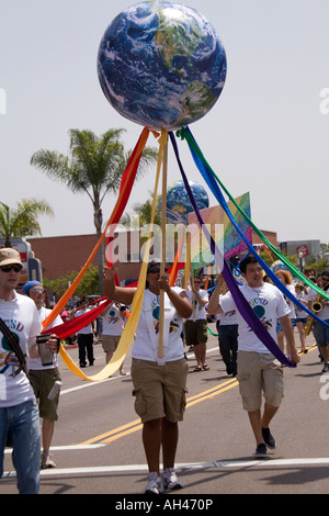 Eine Gruppe von jungen Erwachsenen März in San Diego jährliche Gay Pride Parade, mit einem aufgeblasenen Globus, mit bunten Bändern. Stockfoto