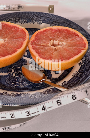 Frisch geschnittene Grapefruit auf einem Teller mit Löffel und Maßband, die gesunde Ernährung, Portionskontrolle und Wellness, USA repräsentieren. Stockfoto