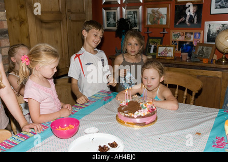 Sechs Jahre alten Glauben mit Schwester und Cousins Ausblasen der Kerzen auf der Geburtstagstorte Cotswolds UK Stockfoto