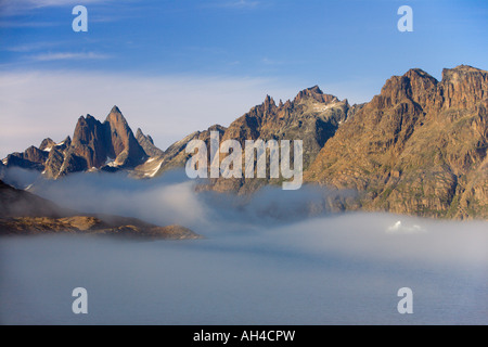 Schroffe Berggipfel und kleiner Eisberg mit wispy Meer Nebel schweben um sie herum in Prins Christiansund Fjord Süd-Grönland Stockfoto