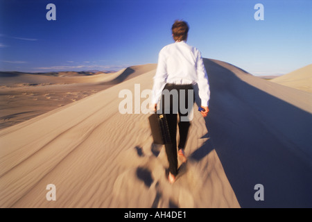 Geschäftsmann mit Aktenkoffer zu Fuß auf Sand Dune in Nevada Stockfoto