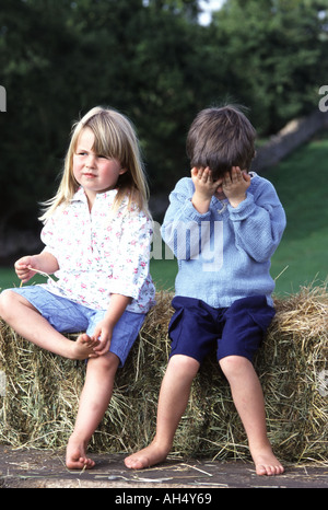 Zwei Kinder sitzen auf einem Strohballen Stockfoto