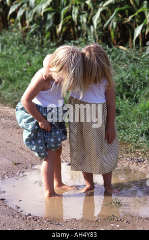 Zwei kleine Mädchen barfuß und stand in einer Pfütze Stockfoto