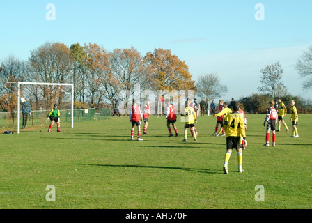 Teenager mit Mannschaftstrikot spielen ein organisiertes Fußballspiel, das von Zuschauern und Eltern Mountnessing Brentwood Essex England beobachtet wird Stockfoto