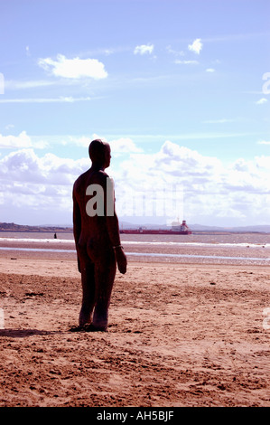 Eines der eisernen Männer Statuen von Gormleys der Ausstellung "Woanders" Blick auf das Meer am Strand Crosby, Merseyside. Stockfoto