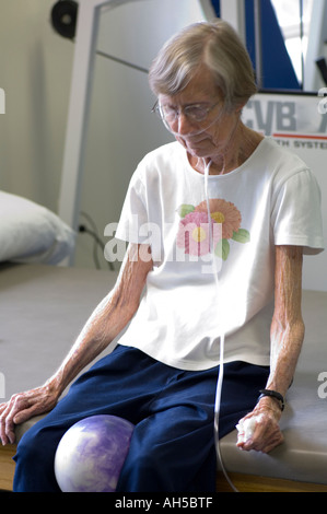 erschöpft, 80 Jahre alte Frau ruht nach Übung Sitzung Krankenhaus Rehabilitationszentrum beim Atmen Sauerstoff aus tragbaren tank Stockfoto