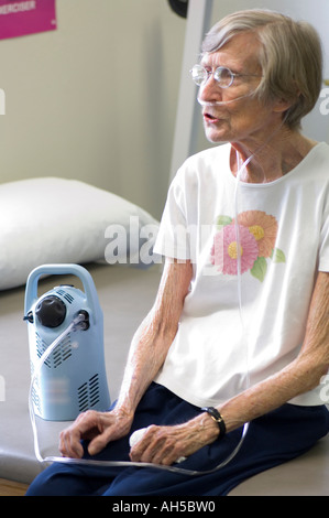 erschöpft, 80 Jahre alte Frau ruht nach Übung Sitzung Krankenhaus Rehabilitationszentrum beim Atmen Sauerstoff aus tragbaren tank Stockfoto