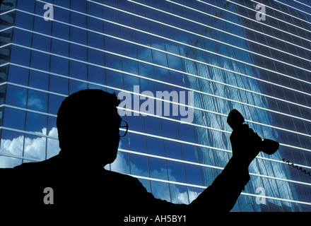 Silhouette der Geschäftsmann auf Telefon mit Hintergrund eines modernen Bürogebäudes Stockfoto
