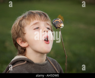 Boy bläst Flammen Marshmallow außerhalb Stockfoto