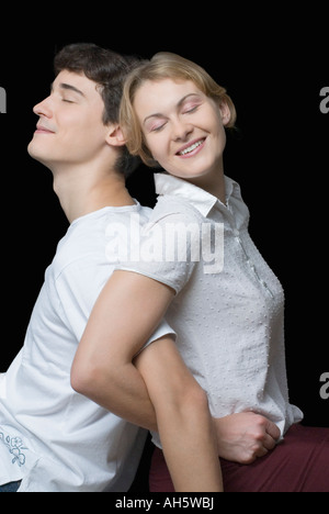 Nahaufnahme von einem jungen Paar Rücken an Rücken mit ihren Armen verriegelt Stockfoto