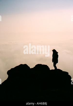 Silhouette der Figur auf Berggipfel über den Wolken Stockfoto