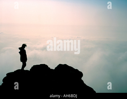 Silhouette der Figur auf Berggipfel über den Wolken Stockfoto