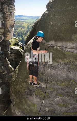 Kletterer Clipping Seil durch eine Schlinge, die durch ein Loch im Felsen, Elbsandsteingebirge, Deutschland eingefädelt ist Stockfoto