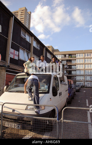 Lebendige Gruppe von Kindern, Klettern und springen auf van auf ihre Wohnsiedlung in Kensal Green West London geparkt. Stockfoto