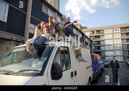 Lebendige Gruppe von Kindern, Klettern und springen auf van auf ihre Wohnsiedlung in Kensal Green West London geparkt. Stockfoto