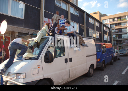 Lebendige Gruppe von Kindern, Klettern und springen auf van auf ihre Wohnsiedlung in Kensal Green West London geparkt. Stockfoto