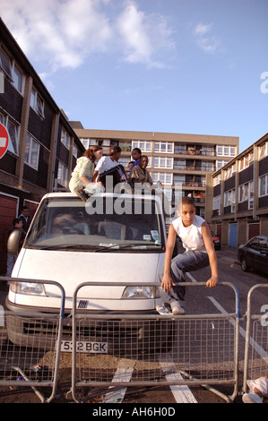 Lebendige Gruppe von Kindern, Klettern und springen auf van auf ihre Wohnsiedlung in Kensal Green West London geparkt. Stockfoto