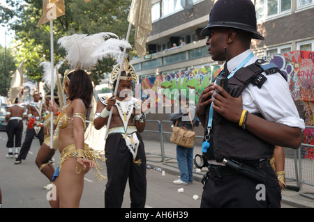 Junge schwarze Polizist Teilnahme in Notting Hill Karneval als Darsteller tanzen und ihn zu necken. Stockfoto