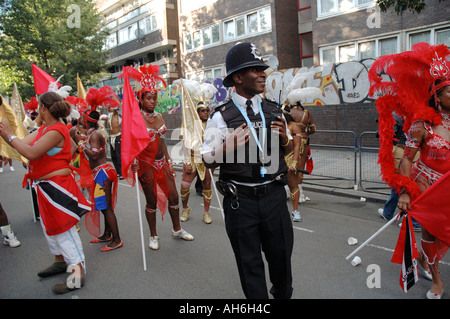 Junge schwarze Polizist Teilnahme in Notting Hill Karneval als Darsteller tanzen und ihn zu necken. Stockfoto