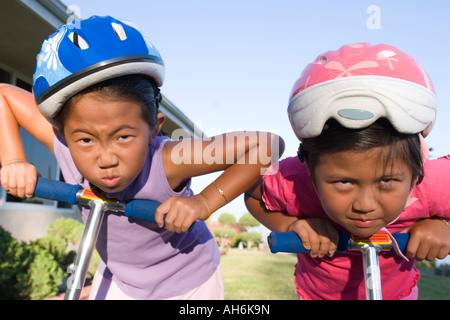 Zwei junge Mädchen auf Roller einen Fahrradhelm tragen Stockfoto