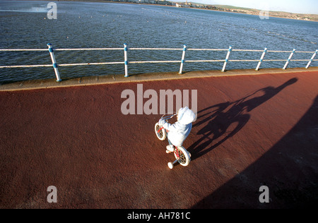 Ein Kind auf einem Fahrrad mit Stabilisatoren wirft einen Schatten versehen Stockfoto