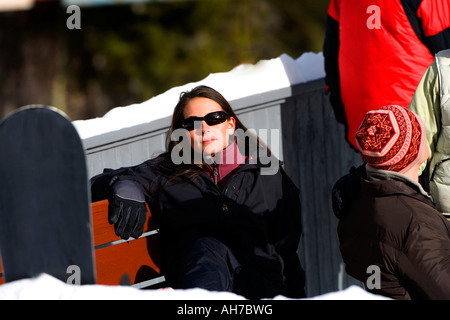 Junge Frau sitzt auf einer Bank mit Sonnenbrille Stockfoto
